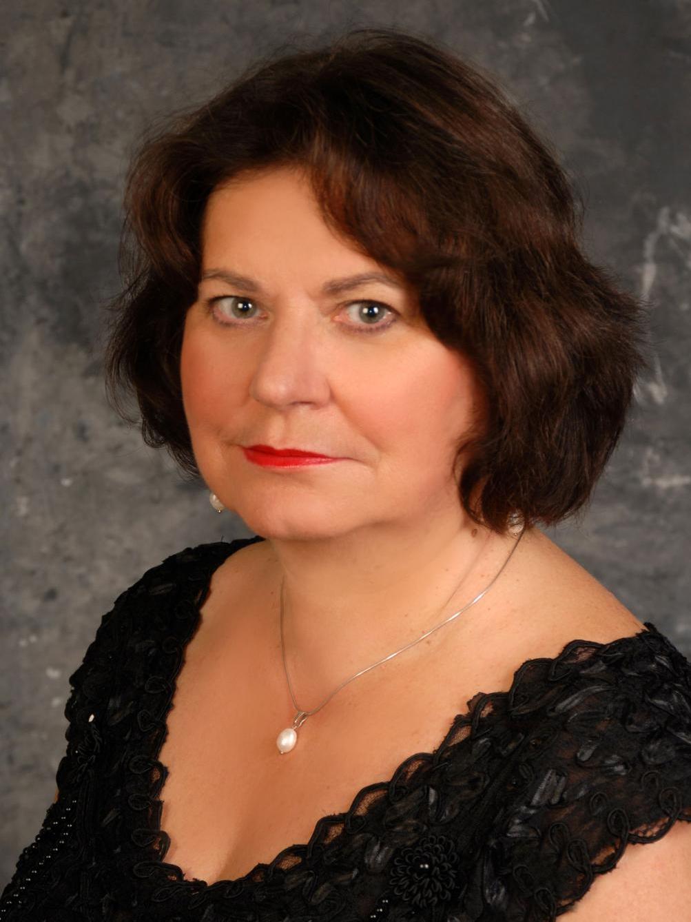 Pianistka Agata Adamczyk pozuje w czarnej sukience i złotym wisorkiem, ma ciemne włosy i usta podkreślone czerwoną szminką